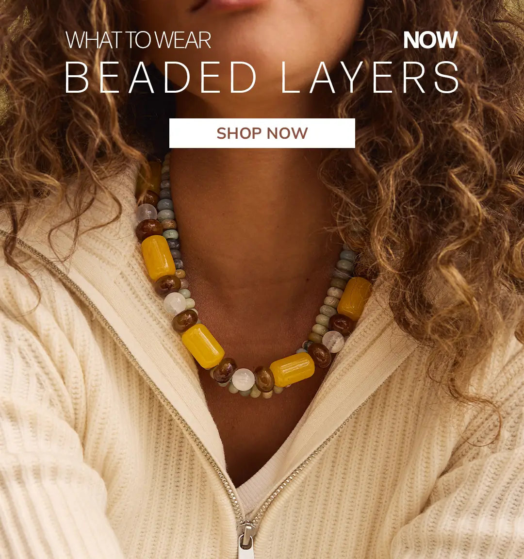 Woman in a cream zip sweater wears a chunky yellow, brown and sage beaded necklace. Text reads “What to wear now: Beaded Layers.” Button: “Shop Now.”