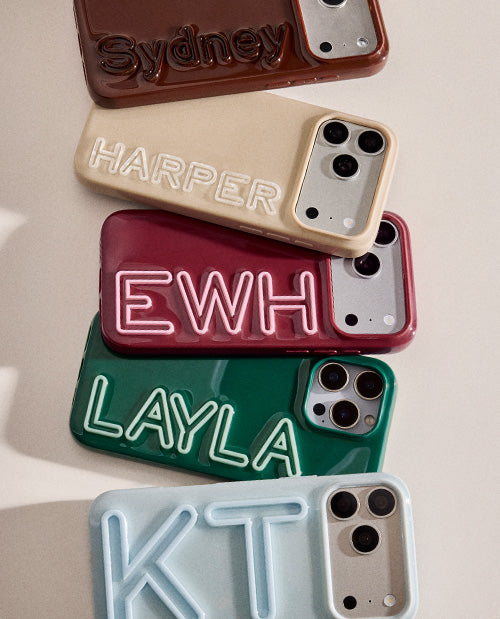 Five personalized phone cases stacked vertically on a light beige background. The cases are in brown, cream, burgundy, forest green, and light blue, each featuring raised, embossed lettering spelling out names or words: 'Sydney', 'HARPER', 'EWH', 'LAYLA', and 'KT'.