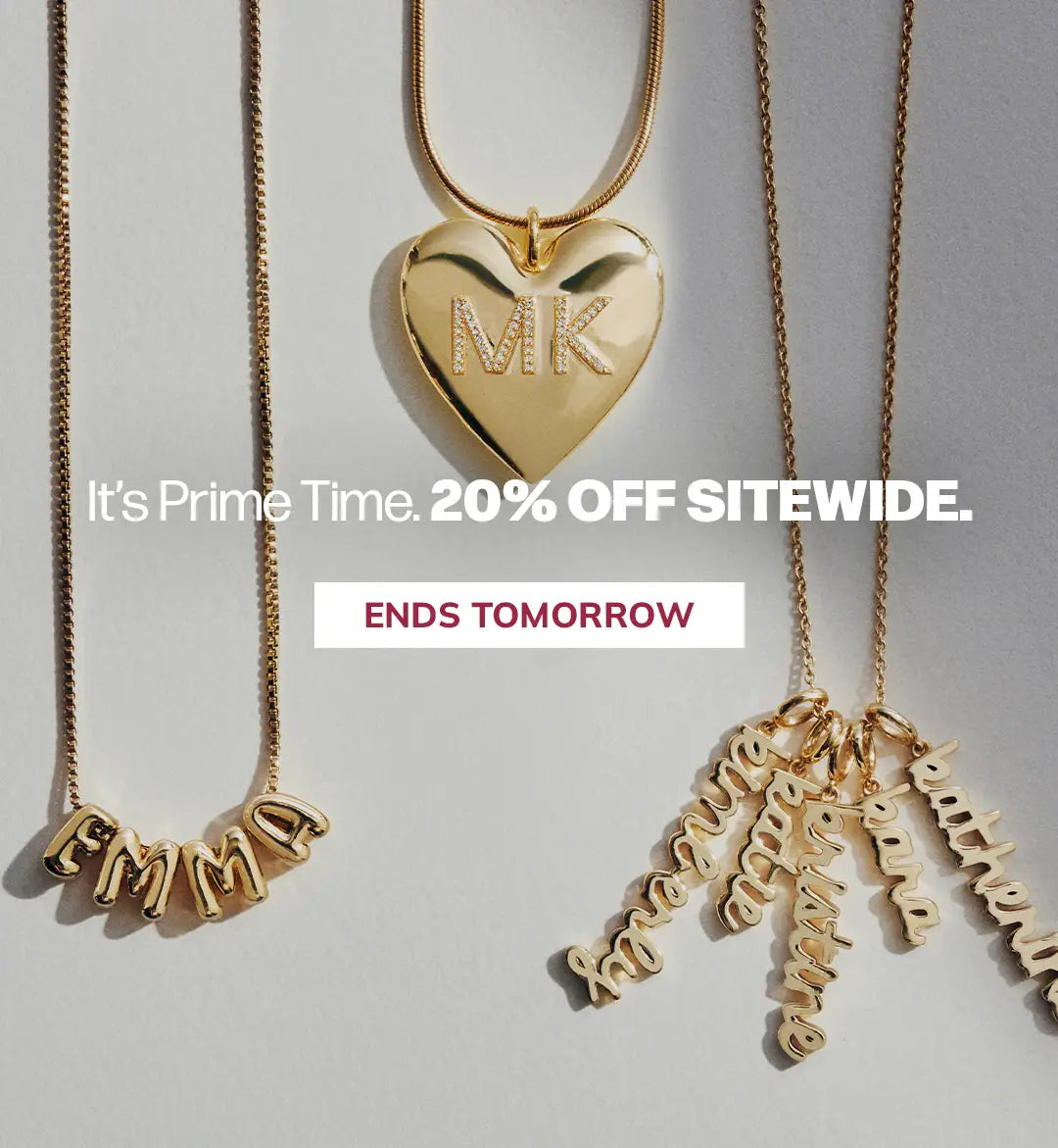Three gold necklaces displayed on a light gray background: a heart-shaped pendant necklace with 'MK' in the center, a nameplate necklace spelling 'EMMA' on the left, and multiple dangling script name charms on the right. White promotional text reads 'It's Prime Time.